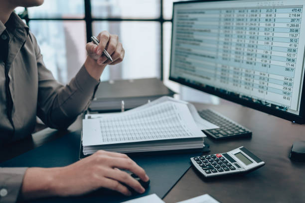 Investors working on desk office and check data cost, balance, profit and  currency on monitor screen. Accounting and  Financial concept. stock photo