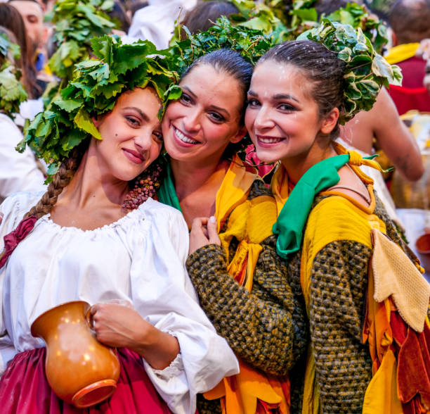 Some young women in colorful period costumes during the Palio celebrations in a medieval town of Umbria Gualdo Tadino, Umbria, Italy, September 30 -- A scene from the traditional Palio di San Michele Arcangelo (Palio of St Archangel Michael) in the medieval town of Gualdo Tadino, in Umbria. An ancient three-day festival that involves the entire community in a traditional Corteo Storico (Historical and Allegoric Parade) and culminates with a donkey race between the four 'contrade' (districts) of this medieval town. In the photo, some young women in a beautiful and colorful medieval costume during the Historical and Allegoric Parade. An important center since Roman times, Gualdo Tadino rises between Foligno and Gubbio along the ancient Flaminia consular road, traced by the Romans. Its history spans the entire Middle Ages and, despite being partially destroyed and sacked several times and placed under the dominion of Perugia, this ancient Umbrian center still retains its medieval charm. The Umbria region, considered the green lung of Italy for its wooded mountains, is characterized by a perfect integration between nature and the presence of man, in a context of environmental sustainability and healthy life. In addition to its immense artistic and historical heritage, Umbria is famous for its food and wine production and for the high quality of the olive oil produced in these lands. Image in high definition format. gualdo tadino stock pictures, royalty-free photos & images
