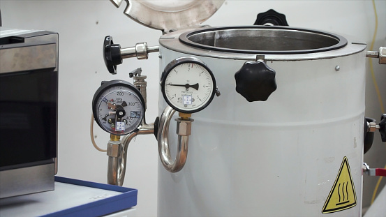 pressure compound gauge psi meter in pipe and valves of water system industrial focus left closeup. technical room for water heating with white boiler and piping system. Temperature gauge of fuel gas systems in power plant