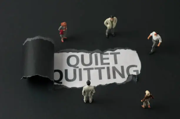 Business people figurines looking at the phrase "Quiet Quitting"
