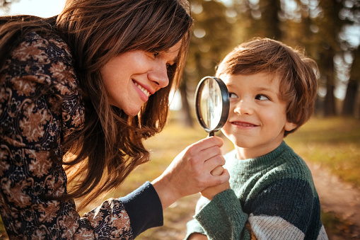 Mother holds a magnifying glass for the boy to look through