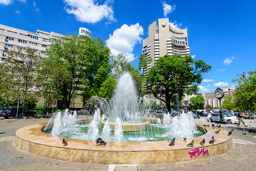 Bucharest, Romania - 6 May 2021: Decorative water fountain near the University Square (Piata Universitatii) in a sunny spring day