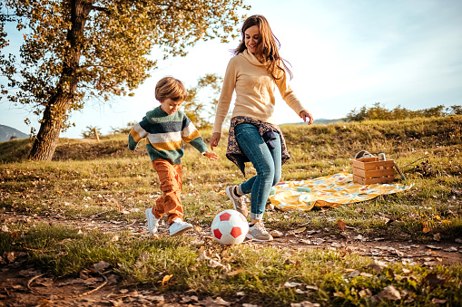Mother and son play football on a beautiful autumn day