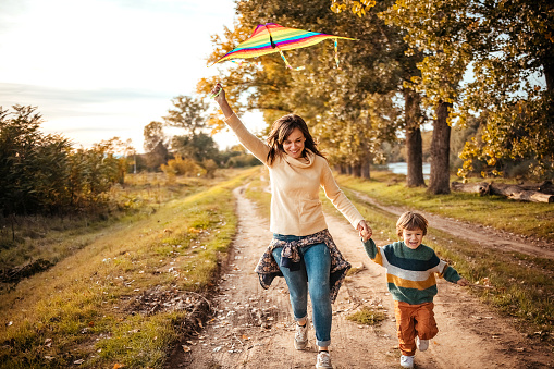 Mother and son flying the kite in a beautiful autumn day