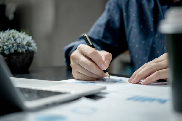 istock male hands with pen over document graph and chart on desk. 1431708053