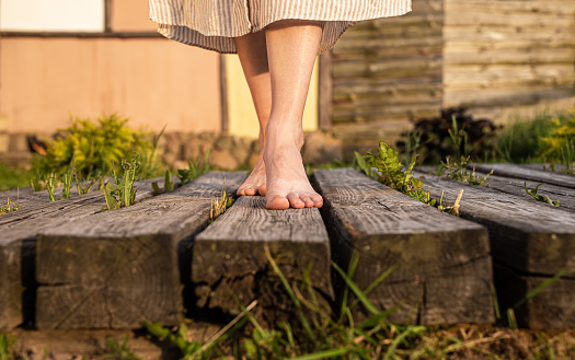 Girls feet walking on wood planks in nature. Women barefoot legs going outdoors. High quality photo