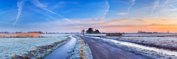 A road through a frosty Dutch polder landscape. Photographed at sunrise. A seamlessly stitched panoramic image.