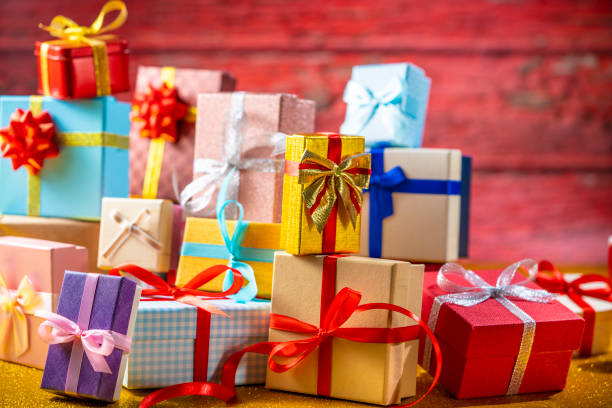 Many gift box stacked as a Christmas gift boxes arrangement on red glitter background with christmas lights