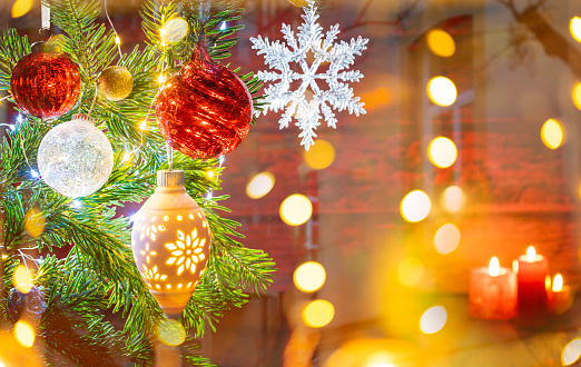 Christmas fir tree background with baubles, snowflake and glowing Christmas lights bokeh