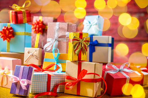 Many gift box stacked as a Christmas gift boxes arrangement on red glitter background with christmas lights