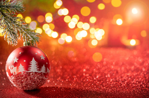 Red bauble with fir tree drawing and Christmas lights on glowing