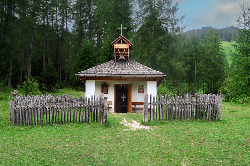 small church in a field in the Val Gardena, Italy, Tyrol, in the foothills of the Dolomite Mountains, surrounded by a hand made wooden fence.
