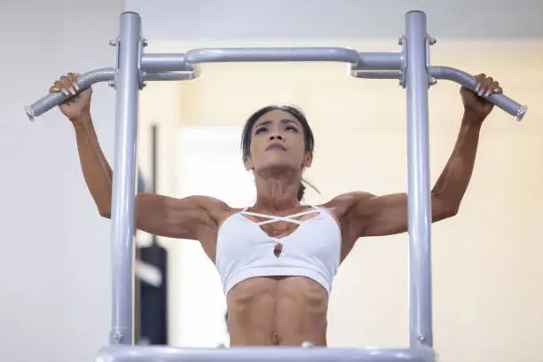 Asian Muscular Woman Pull-Ups Exercise at the Gym.