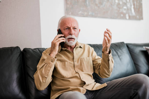 istock Angry senior man using his smart phone and sitting on sofa at living room 1431735425