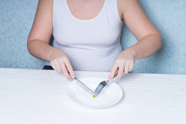 обрезанное изображение девушки, поедающей горох. диета для похудения. расстройство пищевого поведения. - bulimia стоковые фото и изображения