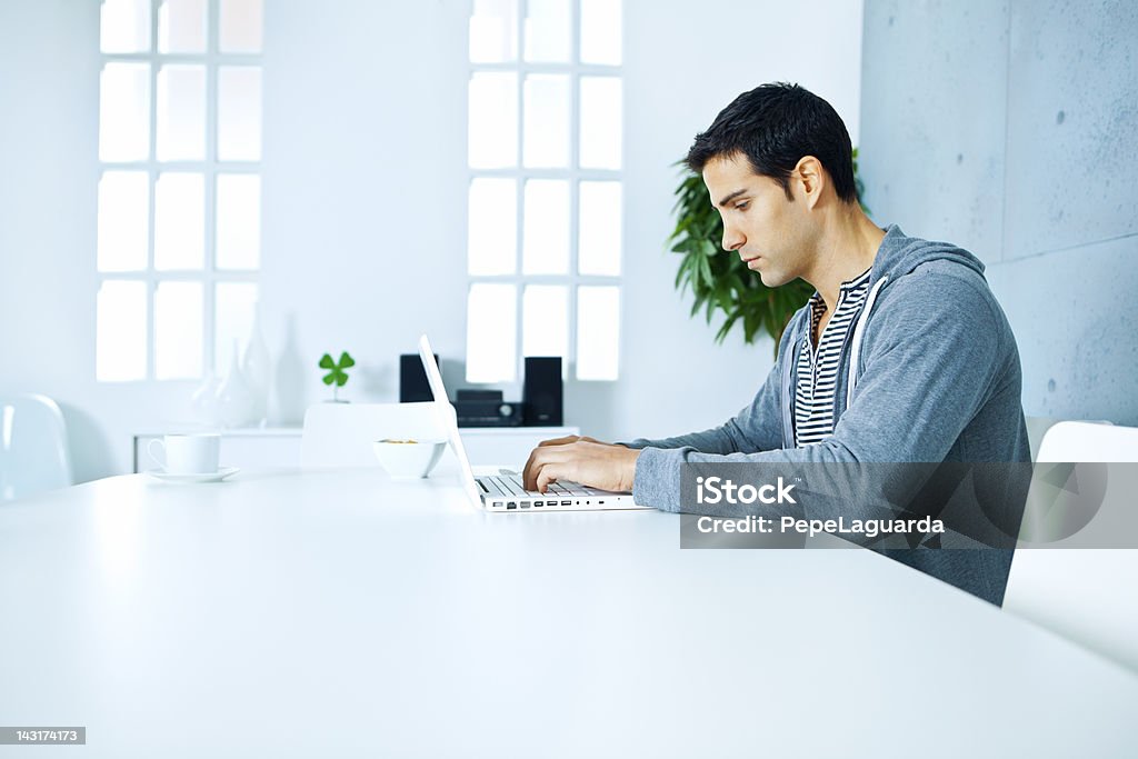 Uomo che lavora con il computer portatile a casa - Foto stock royalty-free di Persone