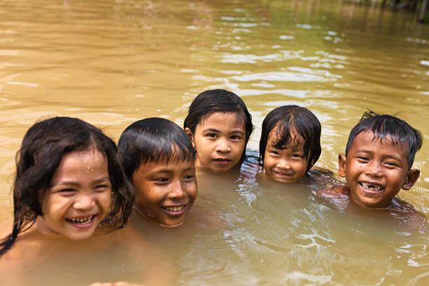 bambini divertirsi in acqua durante l'inondazione, cambogia - flood people asia cambodia foto e immagini stock