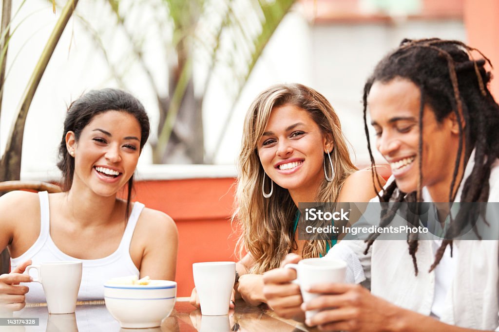 Tres jóvenes y alegres amigos mientras disfruta de la compañía de sus en café. - Foto de stock de Amistad libre de derechos