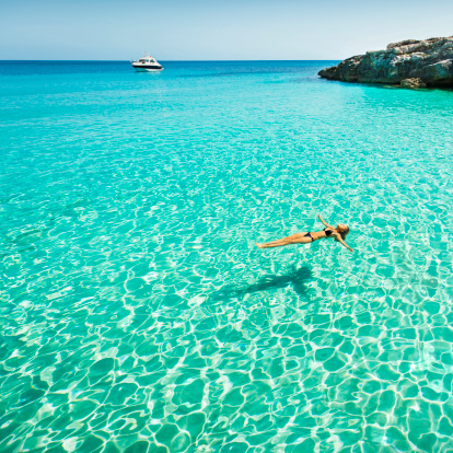 Idyllic holidays: girl floating in fresh clean turquoise water.