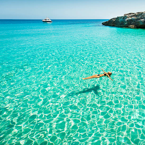 Idyllic holidays Idyllic holidays: girl floating in fresh clean turquoise water. minorca photos stock pictures, royalty-free photos & images