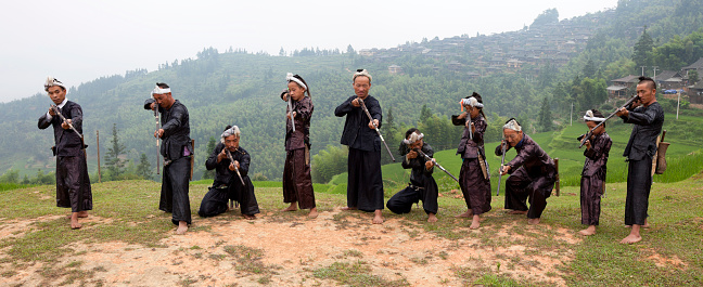 Ten Miao tribe arrogant gunners,background is their village,Biasha (Basha) Miao Village,Congjiang,Guizhou Prrovince,China.