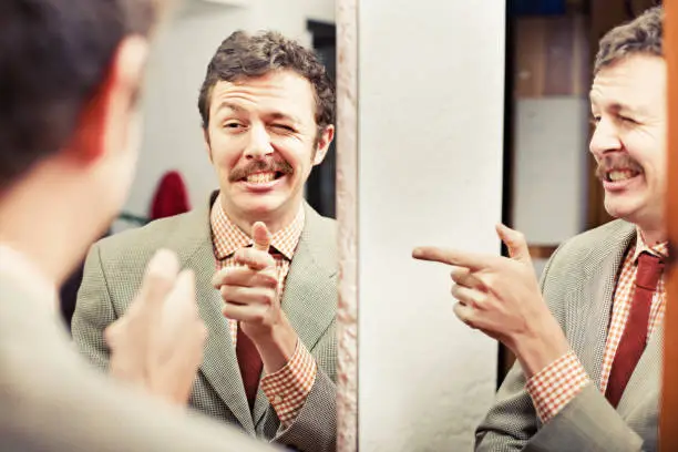 Photo of Man looking at reflection in mirror