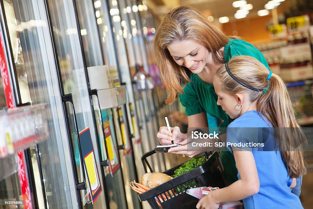 Madre e hija Verificar lista de compras en el supermercado - Foto de stock de Cupón libre de derechos