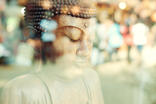 Close up of a Sri Lankan wooden Buddha statue in a window display.