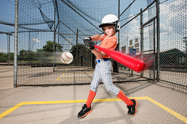 Young Baseball Swing in Batting Cage Action photo of a young boy as he practices for little league baseball by hitting balls in a batting cage. baseball cage stock pictures, royalty-free photos & images