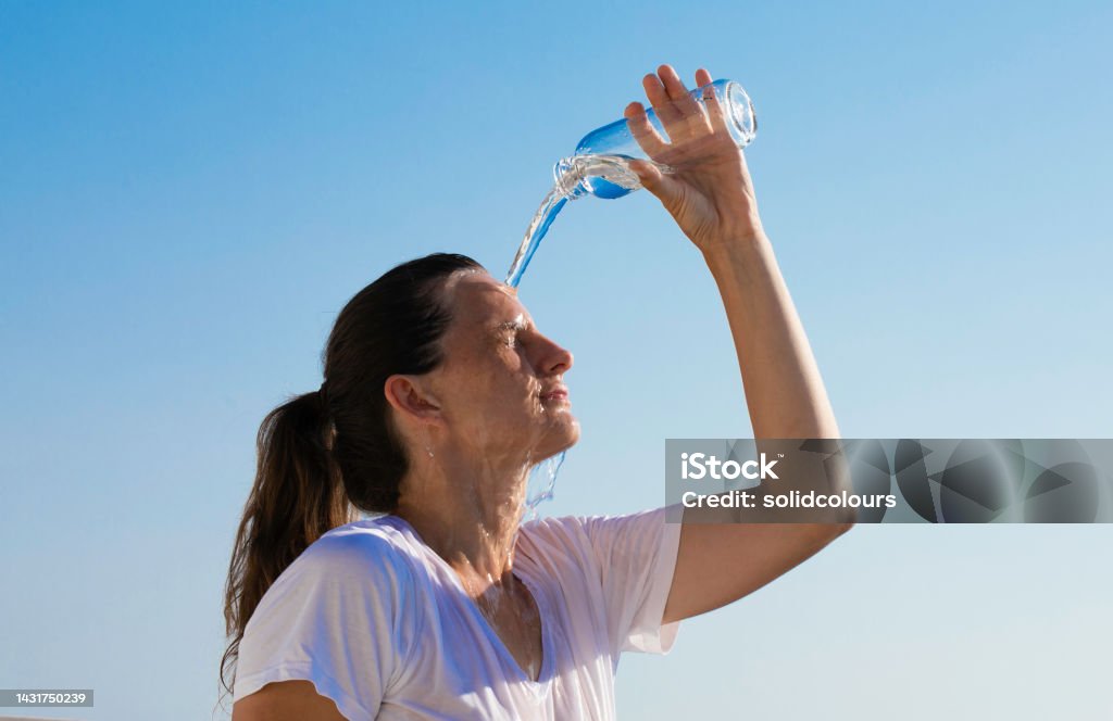 Summer Heat A woman cools down with cold water during the summer heat. Heat - Temperature Stock Photo