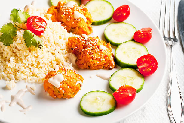 vegan food - homemade balls made from sweet potatoe and chickipea flour, sprinkled with sesame seed, with cucumber and tomatoe, millet, with some sprinkles of sesame sauce
