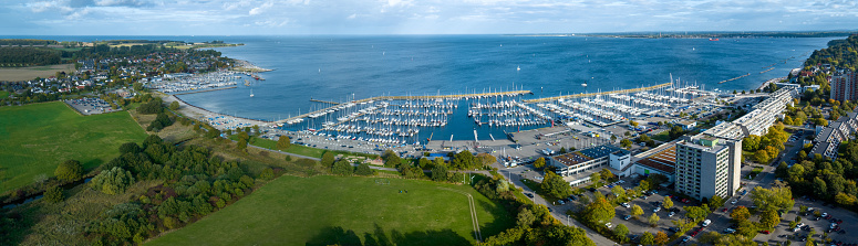 Panorama aerial view of marina Schilksee with sailing boats docked at the pier. Aerial view of popular sailing vacation destination Schilksee with Olympic center with marina on the Baltic Sea.