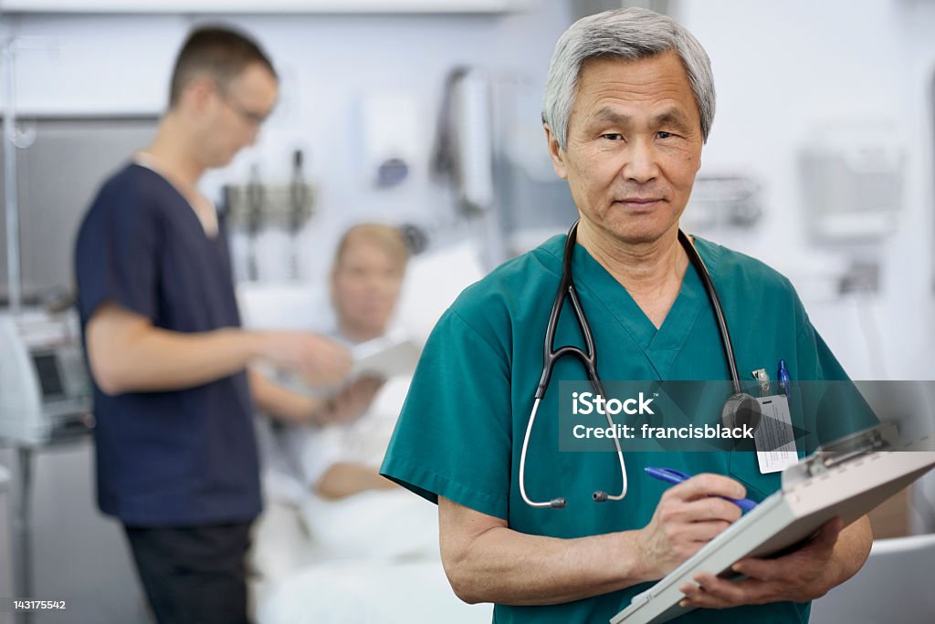 Etniczne lekarza wypełniania kart pacjenta. - Zbiór zdjęć royalty-free (Azjaci)