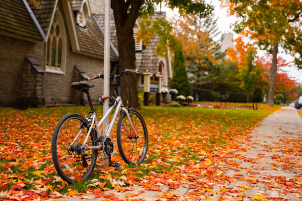 Bicycle parked on sidewalk in front of St. Bartholomew's Anglican Church with golden yellow orange fall leaves all around in Ottawa