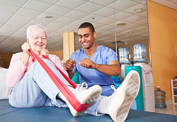 Physical therapist working with patient Physical therapist helping senior woman (80s) with leg exercises. occupational therapy photos stock pictures, royalty-free photos & images