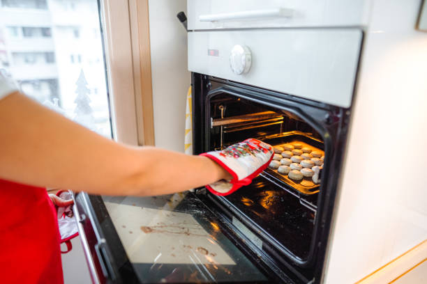 istock Female baker pulling out a tray full of cookies from the oven 1431759226