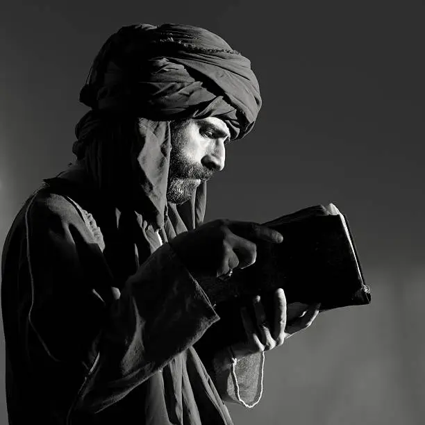 Bearded man with headscarf reading old antique book