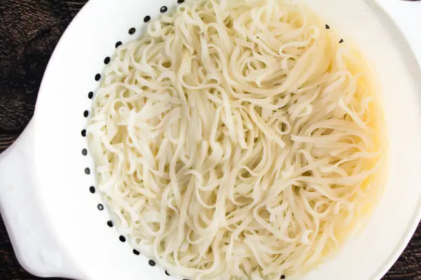 Closeup view from above of cooked noodles in a strainer