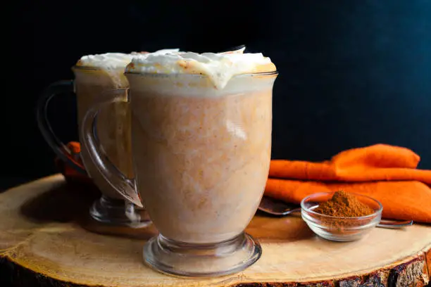 Mugs of hot chocolate topped with chantilly cream and pumpkin spice