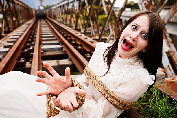 A beautiful young woman in Victorian costume lies screaming for help, tied to the railroad tracks. Behind her a puffing steam train gets nearer and nearer.... classic Victorian melodrama or perhaps a metaphor for abuse of women. 