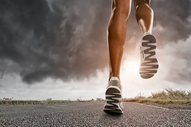 low angle view of female runners legs running down road wearing trainers