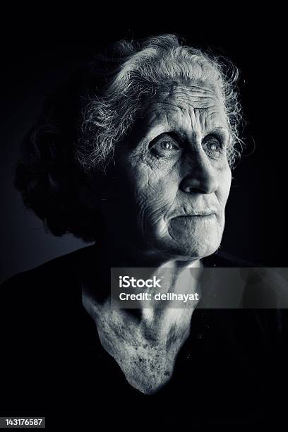 Older Woman Side Portrait In Dark Setting Stock Photo - Download Image Now - Black Background, Contemplation, 60-69 Years