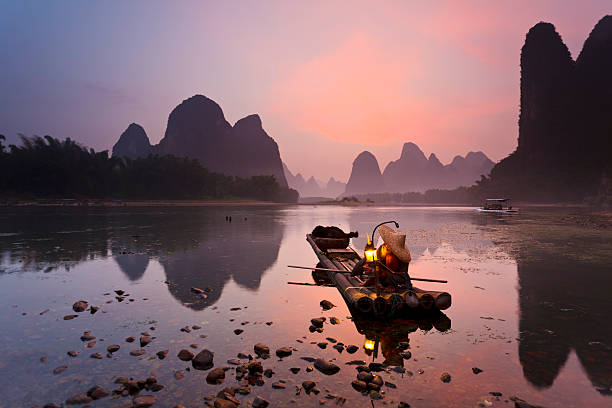 White Beard Cormorant fisherman getting ready for night fishing on the Li River, near Xingping Town, Guangxi province, China. yangshuo stock pictures, royalty-free photos & images