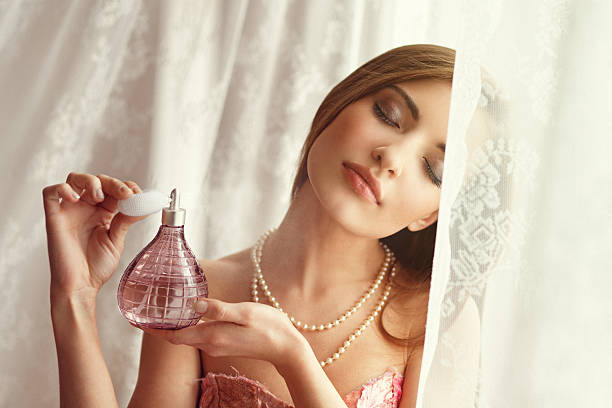 mujer joven aplicar perfume - perfumado fotografías e imágenes de stock