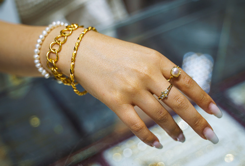 Female hand with gold bracelets and rings, close up