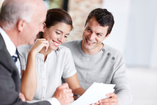 Financial advisor showing a happy young couple a clause in the document
