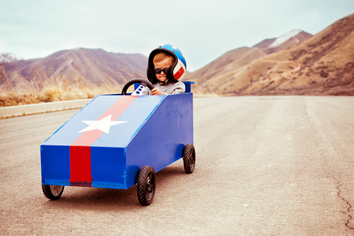 A young boy takes to the slope with his box car to test the limits of speed.