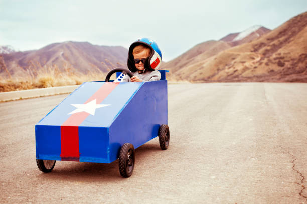 Need for Speed A young boy takes to the slope with his box car to test the limits of speed. soapbox cart stock pictures, royalty-free photos & images