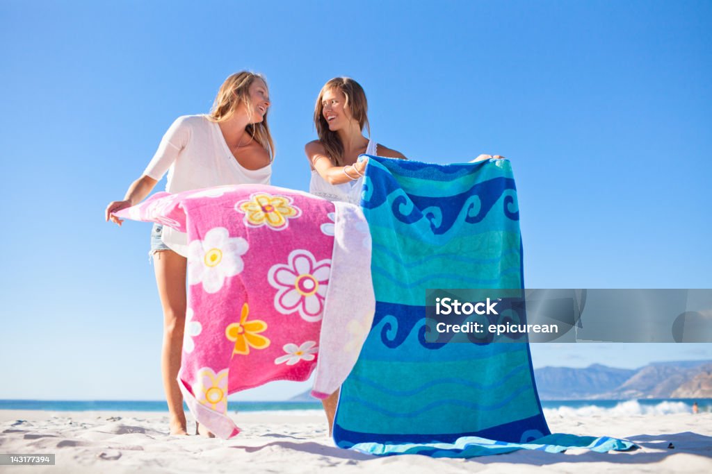 Two attractive teenage girls relaxing and gossiping on the beach  Beach Stock Photo