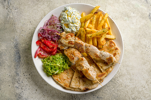 souvlaki with chicken and pita on white plate, Greek cuisine top view on stone table